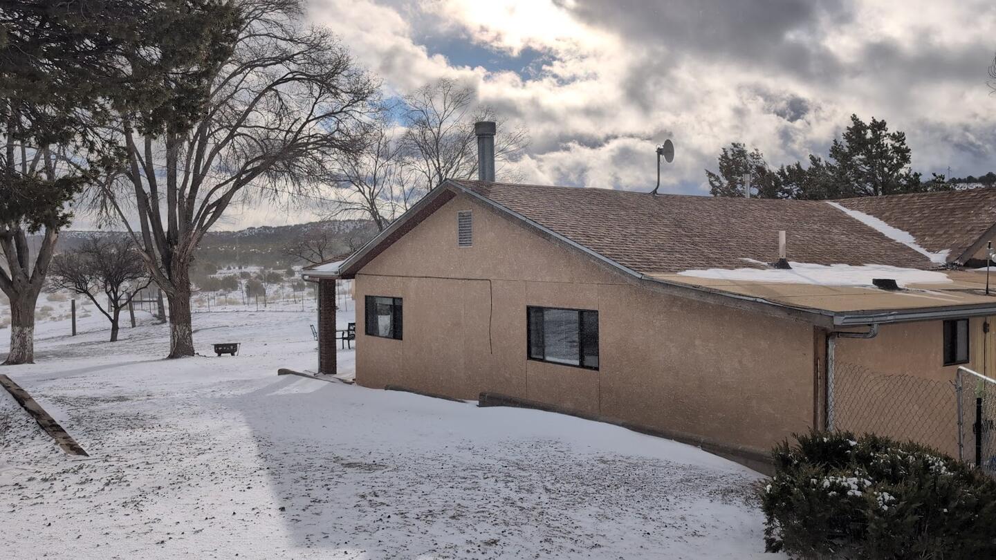The stucco main house in snow beneath storm clouds