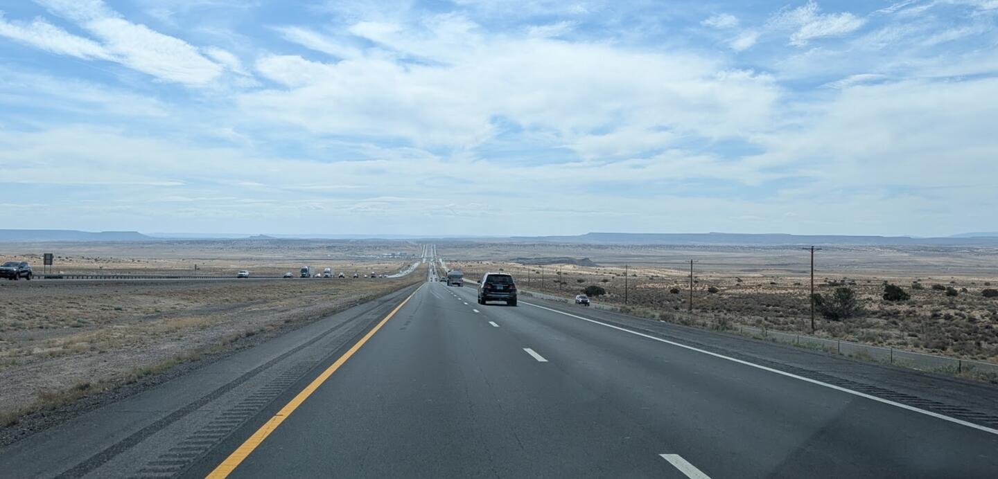 A near-empty interstate through flat desert under a pale sky