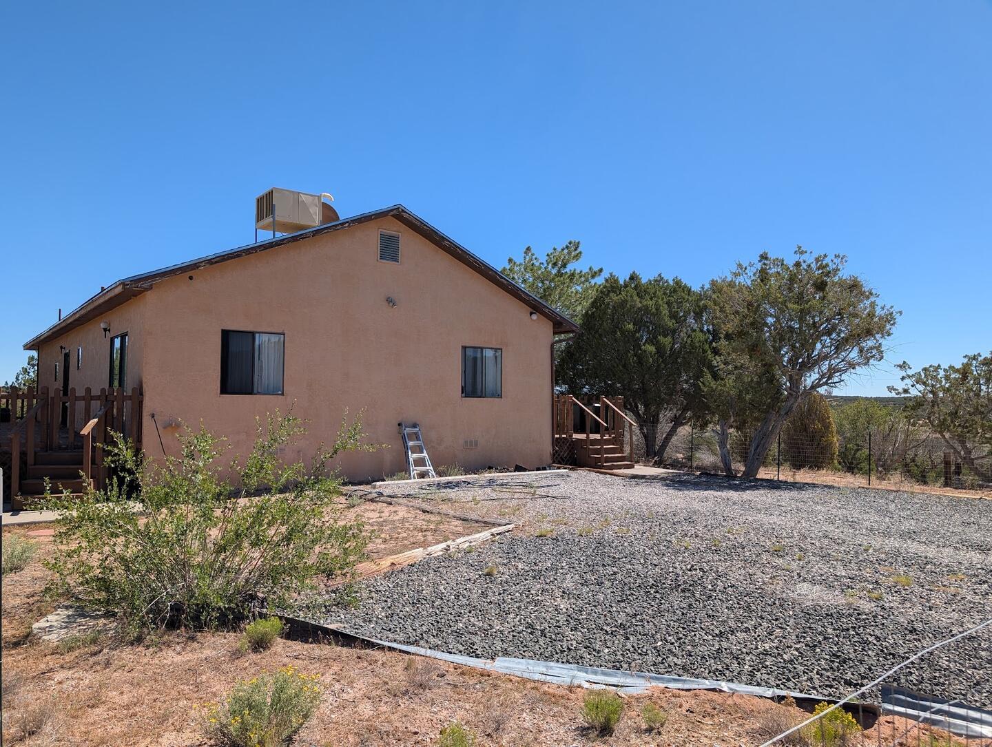 The stucco house with a gravel parking area under a blue sky