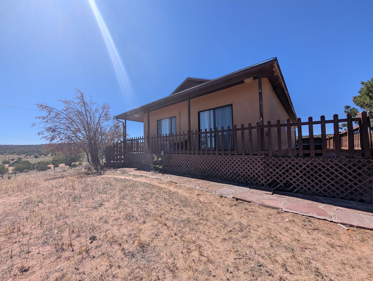 The house with a wooden deck and lattice skirting in bright sun